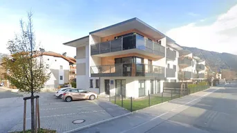 Modernes Mehrfamilienhaus mit Balkonen, Flachdach und Bergblick in einer gepflegten Umgebung.
