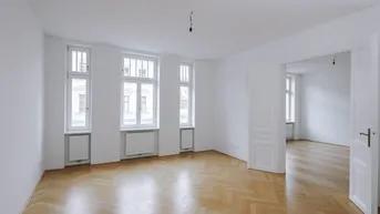 Helles, leeres Zimmer mit Fischgrätparkett und hohen Fenstern, bereit zur Einrichtung.