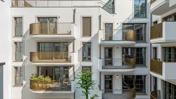 Moderne Wohnfassade mit zahlreichen Balkonen und goldenen Geländern unter blauem Himmel.