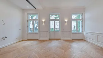Helles Zimmer mit elegantem Fischgrätparkett, hohen Fenstern und klassischer Wandvertäfelung.