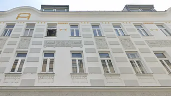 Historische Fassade eines Wohngebäudes mit dekorativen Stuckelementen und Dachgauben.