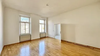 Helles, leeres Zimmer mit glänzendem Parkettboden und zwei hohen Fenstern, bereit zur individuellen Gestaltung.
