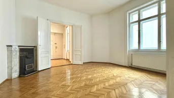 Helles Wohnzimmer mit Fischgrätparkett, hohen Fenstern und einem traditionellen Ofen.
