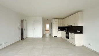 Helle, offene Wohnküche mit modernen cremefarbenen Schränken und Fliesenboden.