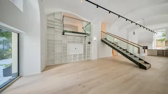 Großzügiger offener Wohnbereich mit hohen Gewölbedecken, moderner Treppe und integriertem Bücherregal.
