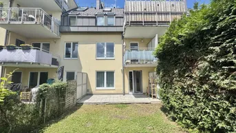 Hinteransicht eines Mehrfamilienhauses mit privatem Gartenbereich und Terrasse im Erdgeschoss.
