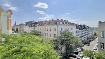 Blick über die Dächer der Stadt mit grünen Bäumen und historischen Gebäuden unter blauem Himmel.