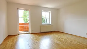 Helles Zimmer mit Parkettboden und Zugang zu einem kleinen Balkon, ideal als Wohn- oder Schlafzimmer.