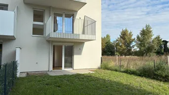Neubauwohnung mit direktem Zugang zu einer gepflasterten Terrasse und einem kleinen Gartenbereich.