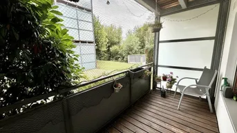 Gemütlicher Balkon mit Holzboden, Sitzgelegenheit und Blick ins Grüne, umgeben von Pflanzen.