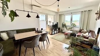 Helles Wohn- und Esszimmer mit Parkettboden, gemütlicher Sitzecke und Blick ins Grüne.