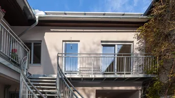 Außenansicht des Gebäudes mit Metalltreppe und Balkonen unter blauem Himmel und Solaranlage auf dem Dach.