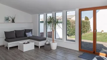 Helles Wohnzimmer mit großen Fenstern und direktem Zugang zum grünen Garten.