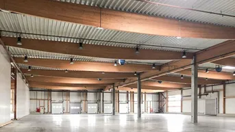 Große, leere Lagerhalle mit hohen Decken, Holzbalken und Betonboden, bereit zur Nutzung.