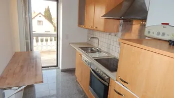 Funktionale Küche mit Holzschränken, Einbaugeräten und Zugang zu einem Balkon mit Aussicht.