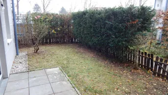 Kleiner privater Gartenbereich mit Rasenfläche, Hecke und gepflasterter Terrasse.