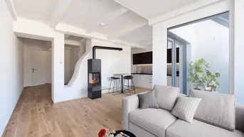 Helles Wohnzimmer mit modernem Kamin, Holzboden und integrierter Küchenzeile, offen gestaltet.