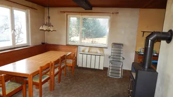 Rustikaler Essbereich mit Holztisch, Eckbank und Kaminofen, bietet eine warme Atmosphäre.