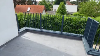 Geräumiger Balkon mit Fliesenboden und Blick auf die Nachbarschaft mit viel Grün.