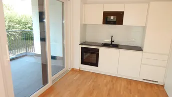 Moderne, helle Küche mit Einbaugeräten, Holzfußboden und direktem Zugang zum Balkon.