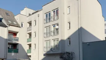 Mehrstöckiges Wohngebäude mit mehreren Balkonen und heller Fassade unter blauem Himmel.