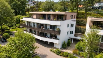 Moderne Wohnanlage mit mehreren Balkonen und Dachterrasse, eingebettet in eine grüne Umgebung.