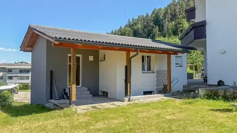 Kleines Nebengebäude mit überdachtem Eingangsbereich und angrenzender Terrasse.