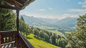 Rustikaler Holzbalkon mit atemberaubendem Blick auf das grüne Tal und die umliegenden Berge.