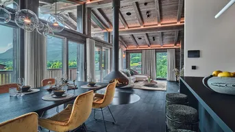 Offener Wohn-Essbereich mit modernem Kamin, Holzbalkendecke und Panoramablick auf die Berge.