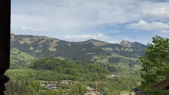 Panoramablick auf die umliegende Berglandschaft und grüne Hügel.
