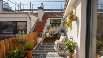 Gemütliche Dachterrasse mit Sitzgelegenheiten, Pflanzen und Blick auf die umliegenden Dächer.
