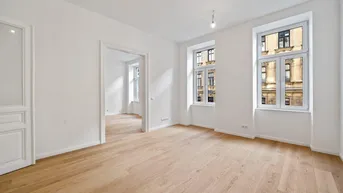 Heller, frisch renovierter Raum mit neuem Parkettboden und hohen Fenstern, die viel Tageslicht hereinlassen.