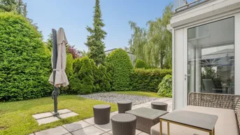 Gemütliche Terrasse mit Gartenmöbeln, umgeben von gepflegten Hecken und Rasenflächen.