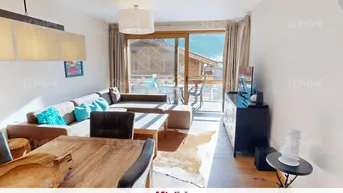 Helles Wohn- und Esszimmer mit gemütlichem Sofa, Holztisch und Zugang zum Balkon mit Bergblick.