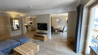 Offener Wohnbereich mit bequemer Couch, Holztisch und Blick auf den Essbereich und die Küche.