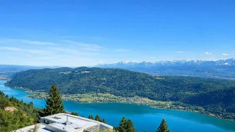 Modernes Haus mit atemberaubendem Blick auf den See und die umliegenden Berge unter blauem Himmel.