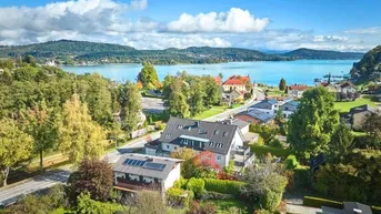 Luftaufnahme eines modernen Wohngebäudes mit Photovoltaikanlage und herrlichem Blick auf den See und die umliegende Landschaft.