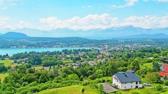 Panoramablick auf den See, die Berge und die umliegende grüne Landschaft mit einem Einfamilienhaus.