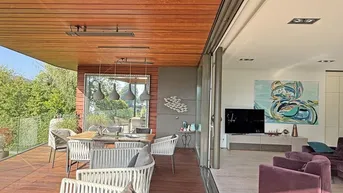 Heller Wohn- und Essbereich mit Zugang zur überdachten Terrasse und weitem Seeblick.