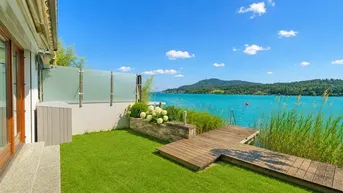 Gepflegter Gartenbereich mit Rasenfläche, Holzsteg und direktem Zugang zum See.