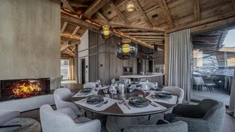 Gemütlicher Essbereich mit modernem Kamin und offener Küche in einem Chalet-Stil Interieur.