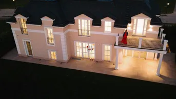 Luxuriöses Haus bei Nacht mit beleuchteter Fassade und großzügiger Terrasse.