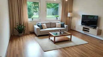 Helles Wohnzimmer mit Laminatboden, beigen Vorhängen und Blick ins Grüne.