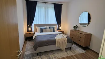 Gemütliches Schlafzimmer mit Doppelbett, Nachttischen, Kommode und Spiegel an der Wand.