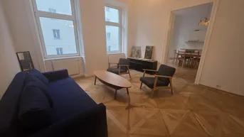 Geräumiges Wohnzimmer mit Parkettboden, bequemer Couch und Blick auf die gegenüberliegenden Gebäude.