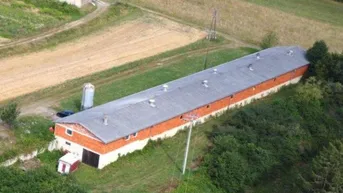 Weitläufige Luftaufnahme eines landwirtschaftlichen Gebäudes in ländlicher Umgebung mit Blick auf entfernte Häuser.
