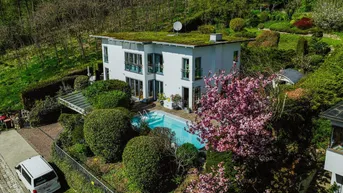 Luftaufnahme eines modernen Hauses mit Gründach, Pool und üppiger Gartenlandschaft.