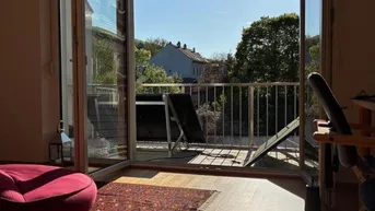 Heller Wohnbereich mit Holzboden und Zugang zu einem sonnigen Balkon mit Photovoltaikmodul.