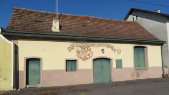 Altes Gebäude mit verputzter Fassade, Ziegeldach und historischen Holztüren.