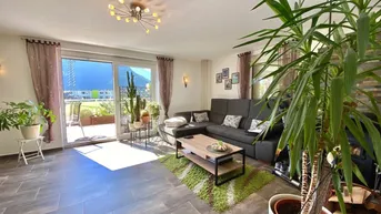 Helles Wohnzimmer mit großem Sofa, Fliesenboden und Zugang zur Terrasse mit Bergblick.